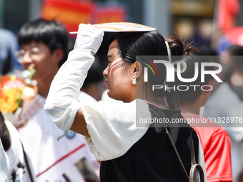 Citizens are wearing sun-protective clothing and riding on a street under high temperatures in Fuyang, China, on June 14, 2024. (