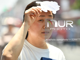 Citizens are wearing sun-protective clothing and riding on a street under high temperatures in Fuyang, China, on June 14, 2024. (