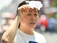 Citizens are wearing sun-protective clothing and riding on a street under high temperatures in Fuyang, China, on June 14, 2024. (