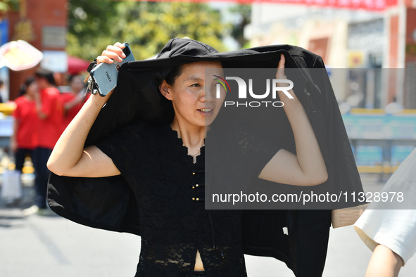 Citizens are wearing sun-protective clothing and riding on a street under high temperatures in Fuyang, China, on June 14, 2024. 