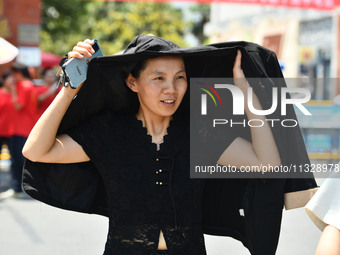 Citizens are wearing sun-protective clothing and riding on a street under high temperatures in Fuyang, China, on June 14, 2024. (