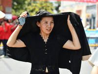 Citizens are wearing sun-protective clothing and riding on a street under high temperatures in Fuyang, China, on June 14, 2024. (