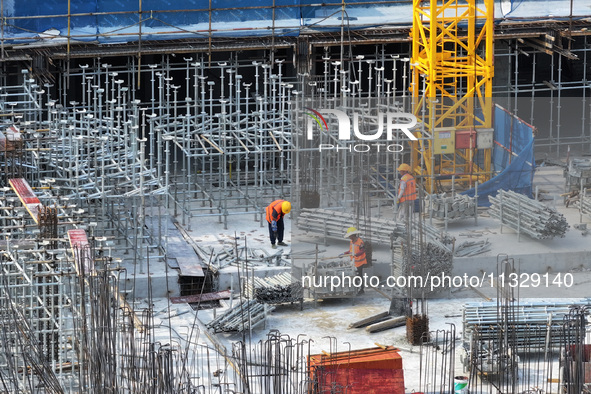 Workers are working outdoors at a commercial housing construction site in Nanjing, China, on June 14, 2024, when the temperature is exceedin...