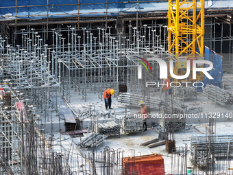 Workers are working outdoors at a commercial housing construction site in Nanjing, China, on June 14, 2024, when the temperature is exceedin...