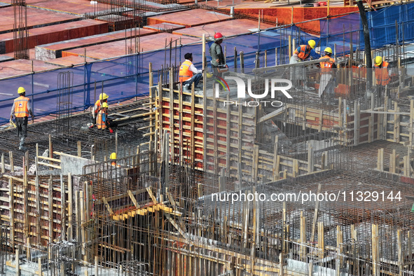 Workers are working outdoors at a commercial housing construction site in Nanjing, China, on June 14, 2024, when the temperature is exceedin...