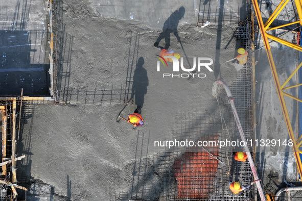 Workers are working outdoors at a commercial housing construction site in Nanjing, China, on June 14, 2024, when the temperature is exceedin...