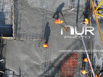 Workers are working outdoors at a commercial housing construction site in Nanjing, China, on June 14, 2024, when the temperature is exceedin...