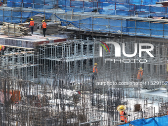 Workers are working outdoors at a commercial housing construction site in Nanjing, China, on June 14, 2024, when the temperature is exceedin...