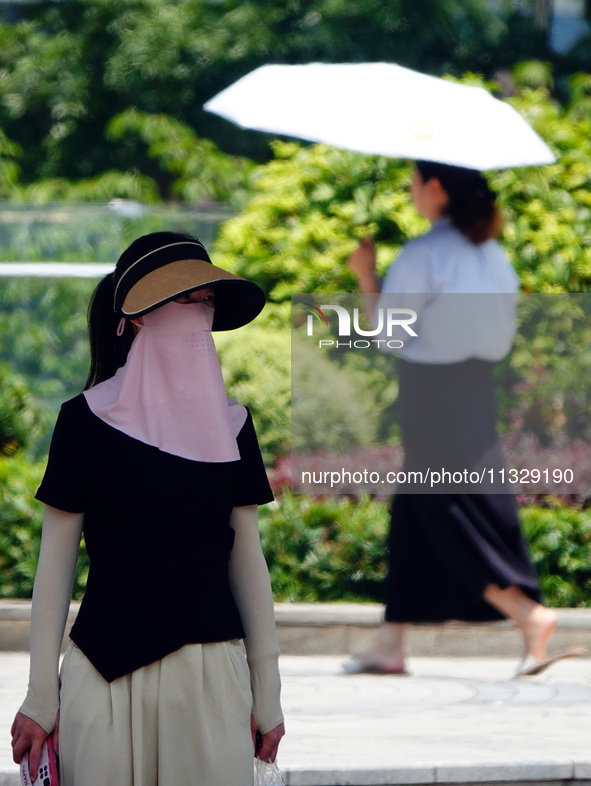 Citizens are wearing sun protection clothes to travel in Yichang, China, on June 14, 2024. 