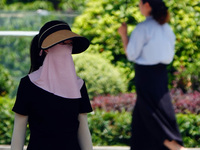 Citizens are wearing sun protection clothes to travel in Yichang, China, on June 14, 2024. (