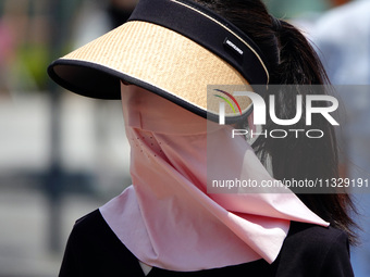 Citizens are wearing sun protection clothes to travel in Yichang, China, on June 14, 2024. (