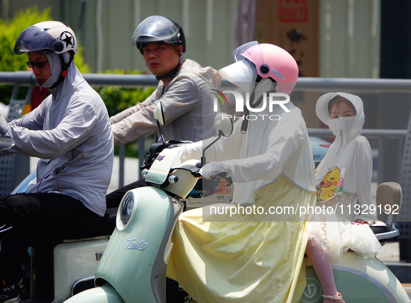 Citizens are wearing sun protection clothes to travel in Yichang, China, on June 14, 2024. 