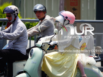 Citizens are wearing sun protection clothes to travel in Yichang, China, on June 14, 2024. (