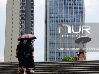 Citizens are wearing sun protection clothes to travel in Yichang, China, on June 14, 2024. (