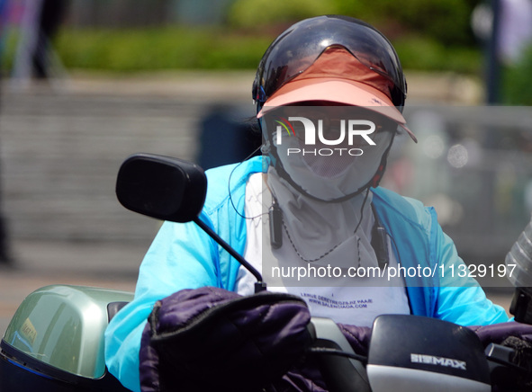 Citizens are wearing sun protection clothes to travel in Yichang, China, on June 14, 2024. 