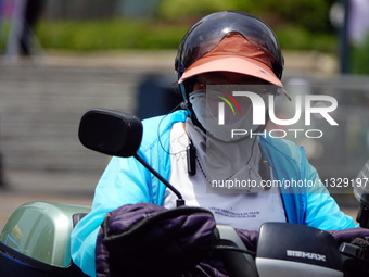 Citizens are wearing sun protection clothes to travel in Yichang, China, on June 14, 2024. (