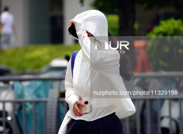 Citizens are wearing sun protection clothes to travel in Yichang, China, on June 14, 2024. 