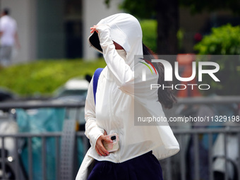 Citizens are wearing sun protection clothes to travel in Yichang, China, on June 14, 2024. (