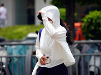 Citizens are wearing sun protection clothes to travel in Yichang, China, on June 14, 2024. (