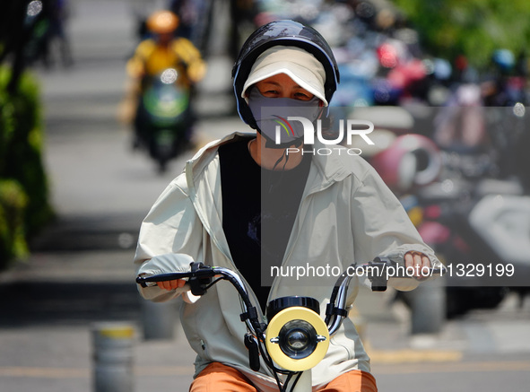 Citizens are wearing sun protection clothes to travel in Yichang, China, on June 14, 2024. 