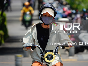 Citizens are wearing sun protection clothes to travel in Yichang, China, on June 14, 2024. (