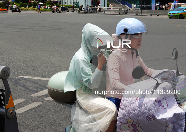 Citizens are wearing sun protection clothes to travel in Yichang, China, on June 14, 2024. 