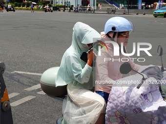 Citizens are wearing sun protection clothes to travel in Yichang, China, on June 14, 2024. (