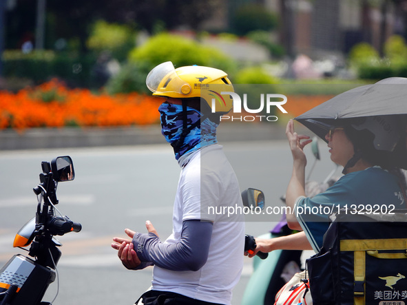 Citizens are wearing sun protection clothes to travel in Yichang, China, on June 14, 2024. 