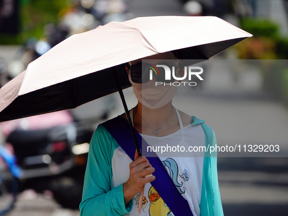 Citizens are wearing sun protection clothes to travel in Yichang, China, on June 14, 2024. 