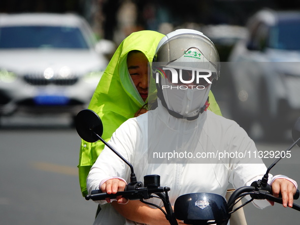 Citizens are wearing sun protection clothes to travel in Yichang, China, on June 14, 2024. 