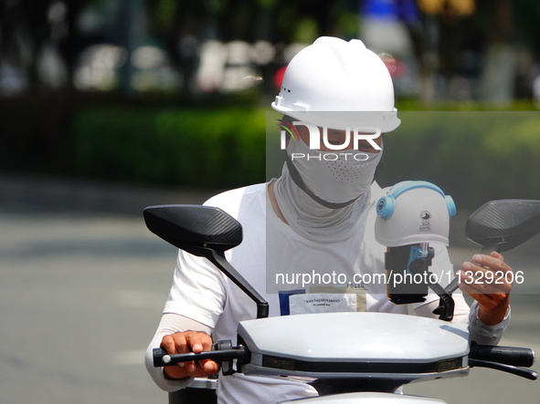 Citizens are wearing sun protection clothes to travel in Yichang, China, on June 14, 2024. 