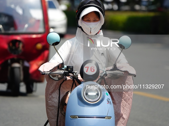 Citizens are wearing sun protection clothes to travel in Yichang, China, on June 14, 2024. 