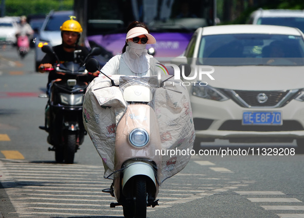 Citizens are wearing sun protection clothes to travel in Yichang, China, on June 14, 2024. 