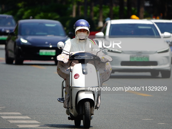 Citizens are wearing sun protection clothes to travel in Yichang, China, on June 14, 2024. 