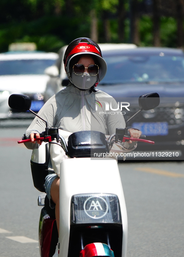 Citizens are wearing sun protection clothes to travel in Yichang, China, on June 14, 2024. 