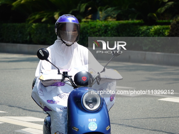 Citizens are wearing sun protection clothes to travel in Yichang, China, on June 14, 2024. 