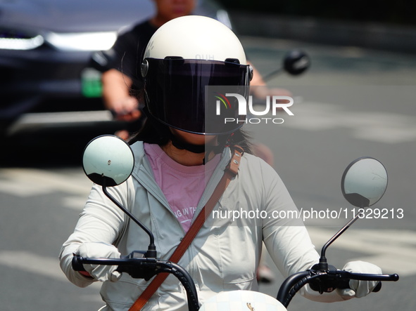 Citizens are wearing sun protection clothes to travel in Yichang, China, on June 14, 2024. 