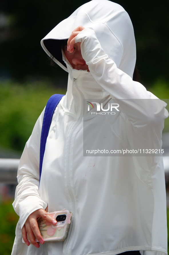 Citizens are wearing sun protection clothes to travel in Yichang, China, on June 14, 2024. 