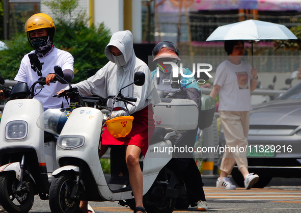 Citizens are wearing sun protection clothes to travel in Yichang, China, on June 14, 2024. 