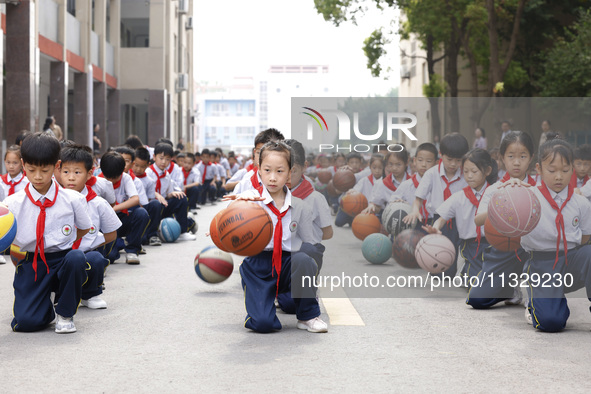 Primary school students are demonstrating basketball exercises at a school in Suqian, Jiangsu province, China, on June 14, 2024. 