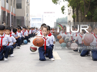 Primary school students are demonstrating basketball exercises at a school in Suqian, Jiangsu province, China, on June 14, 2024. (