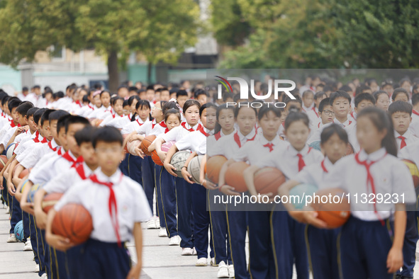 Primary school students are demonstrating basketball exercises at a school in Suqian, Jiangsu province, China, on June 14, 2024. 