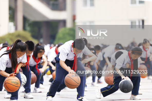 Primary school students are demonstrating basketball exercises at a school in Suqian, Jiangsu province, China, on June 14, 2024. 