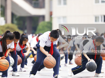 Primary school students are demonstrating basketball exercises at a school in Suqian, Jiangsu province, China, on June 14, 2024. (