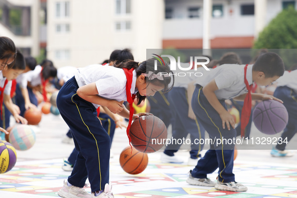 Primary school students are demonstrating basketball exercises at a school in Suqian, Jiangsu province, China, on June 14, 2024. 