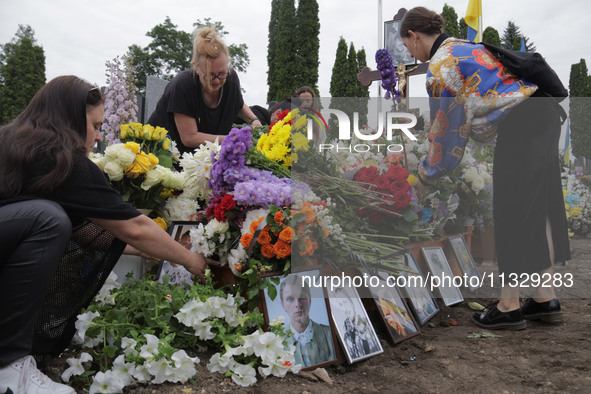 Women are laying flowers at the grave of Ukrainian serviceman, artist, musician, stylist, and queer community member Artur Snitkus, 36, who...