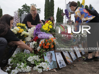 Women are laying flowers at the grave of Ukrainian serviceman, artist, musician, stylist, and queer community member Artur Snitkus, 36, who...