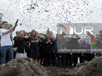 People are launching confetti from party poppers during the funeral of Ukrainian serviceman, artist, musician, stylist, and queer community...