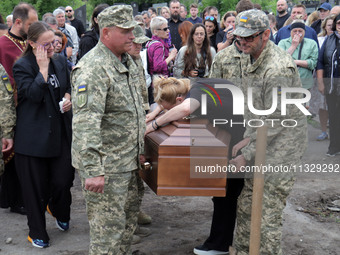 A woman is mourning by the coffin of Ukrainian serviceman, artist, musician, stylist, and queer community member Artur Snitkus, 36, who peri...