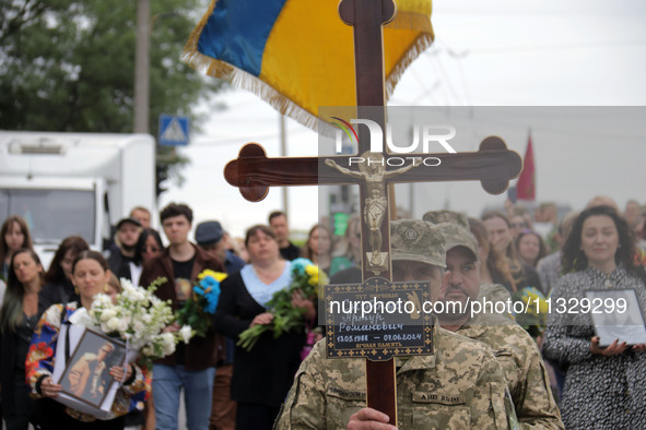 A soldier is carrying the cross as the funeral procession of Ukrainian serviceman, artist, musician, stylist, and queer community member Art...